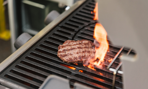 Burger being grilled on a propane grill