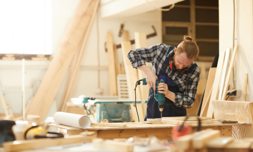 Carpenter drilling millwork in a wood shop